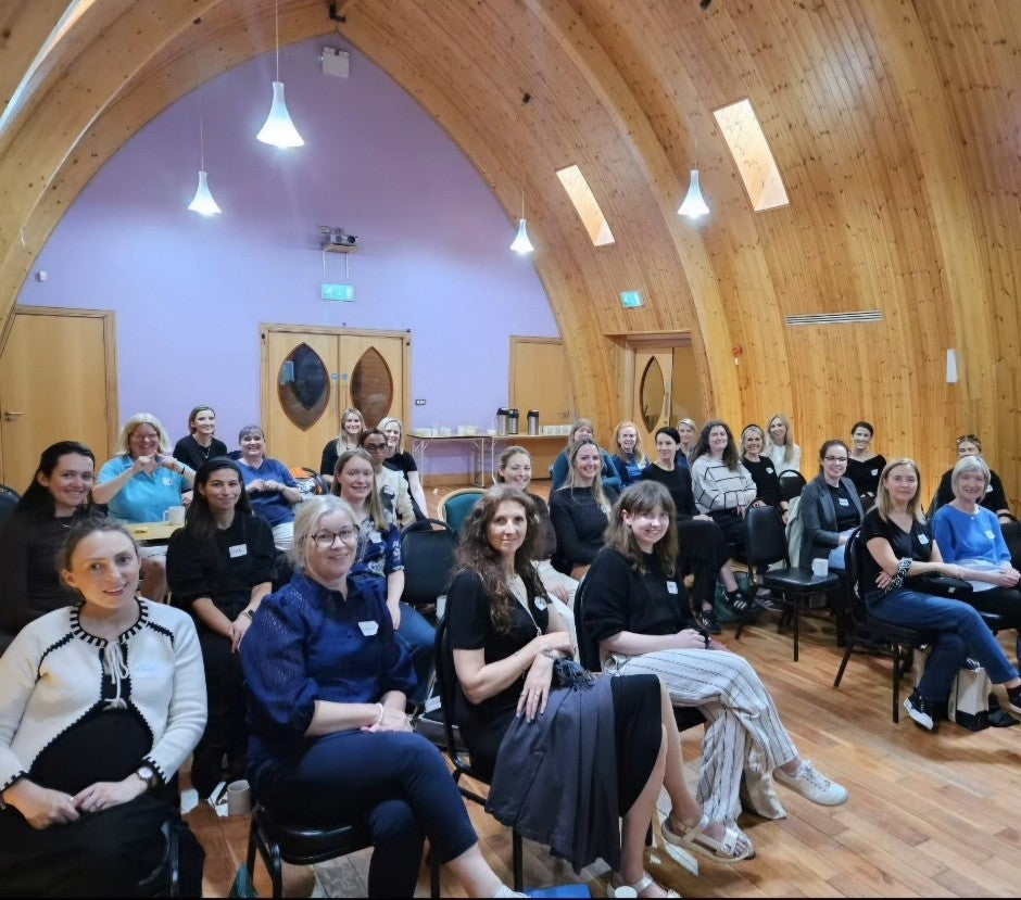 Group of people sitting in a wooden hall with arched ceilings