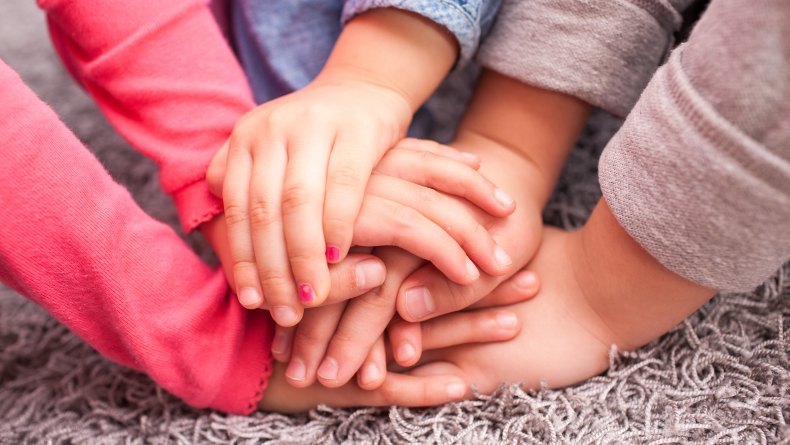 image shows a group of children resting their hands on top of each other